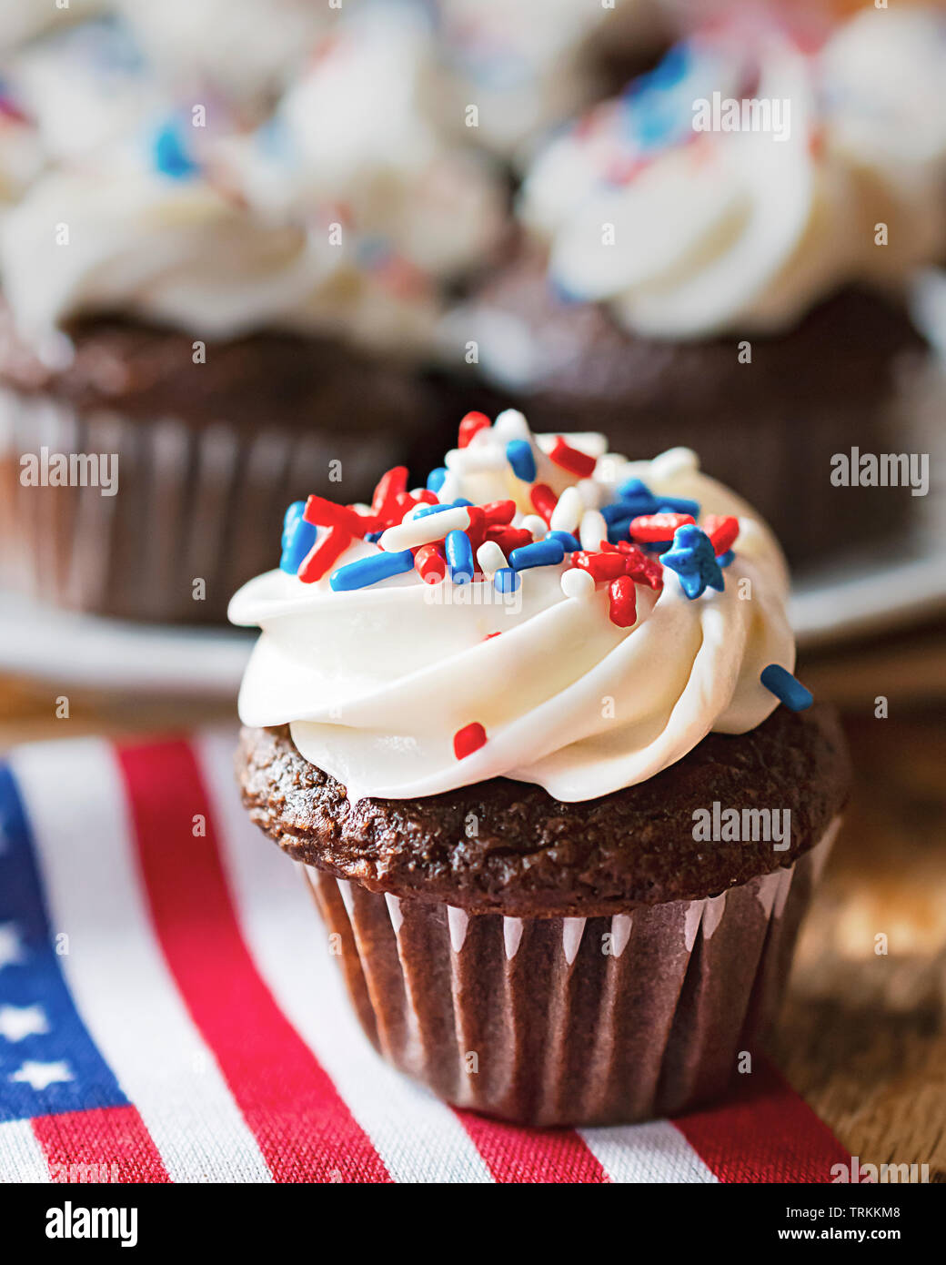 Close up di mini cupcake decorate con rosso, bianco e blu spruzza su una miniatura di noi bandiera. Ulteriori tortine sfocati in background. Foto Stock