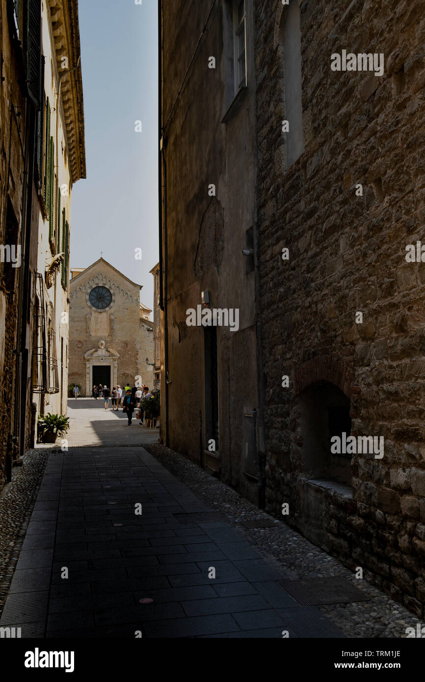 Vicolo stretto con una vista della St Michael cattedrale. Albenga, Liguria. Foto Stock