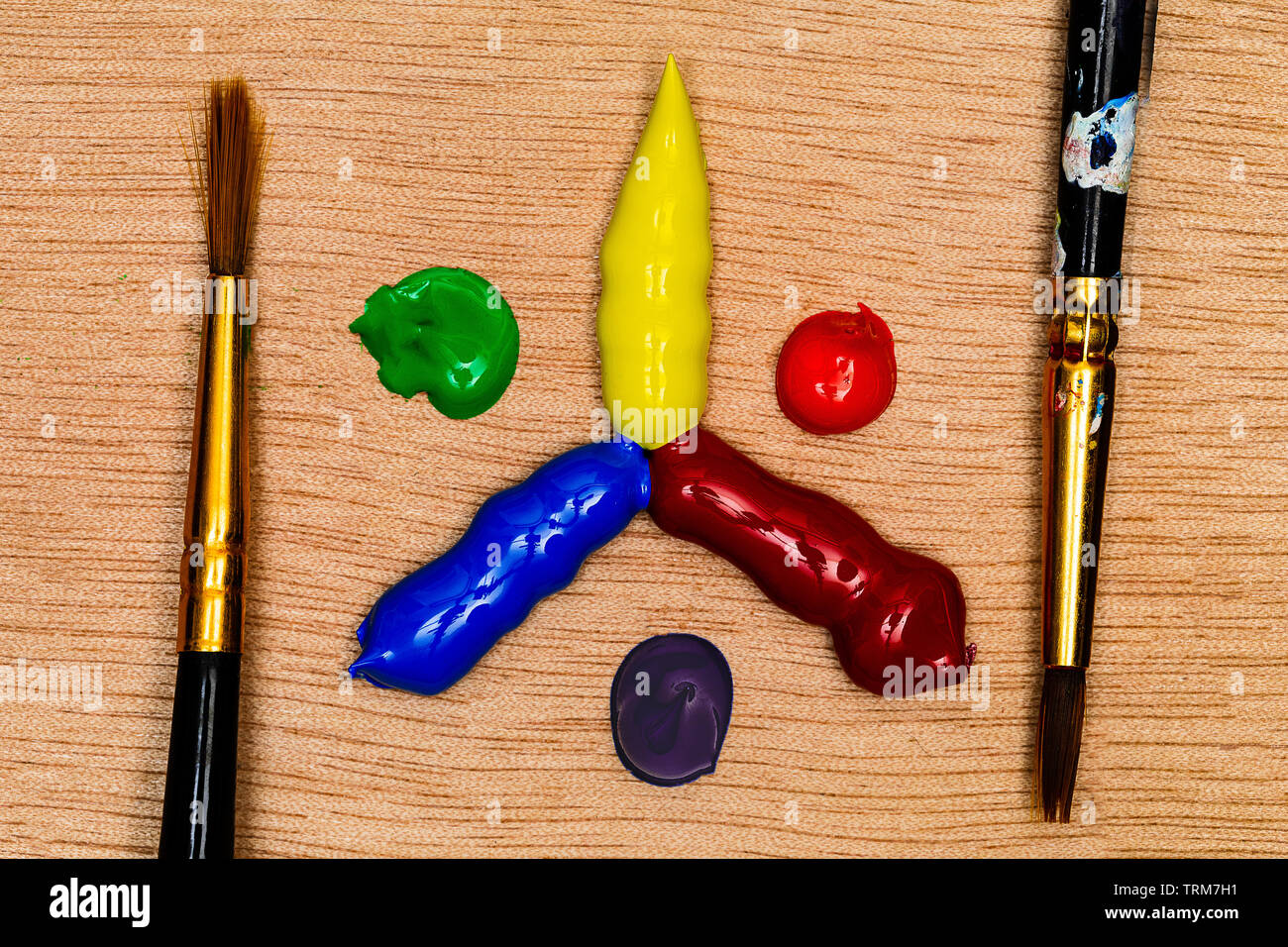 Un colore primario e secondario ruota realizzati di blob di vernice acrilica con due artista spazzole pronto per l'uso, tutte su una tavolozza di legno. I colori sono molto v Foto Stock