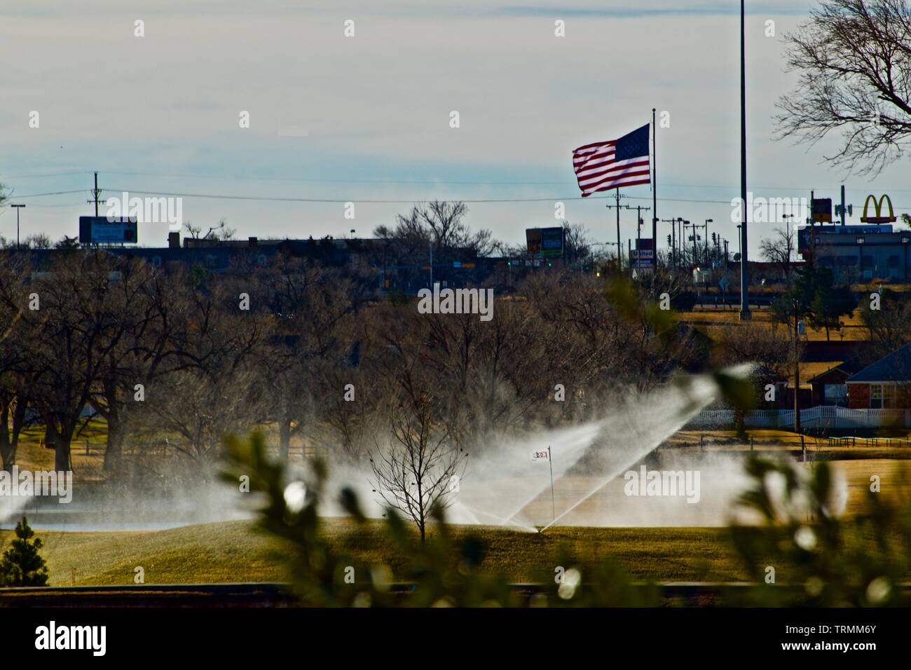 Città di Canyon Mega-Flag al di sopra dello skyline della città e sprinkler acqua di città di Campo da Golf, Canyon, Texas. Foto Stock