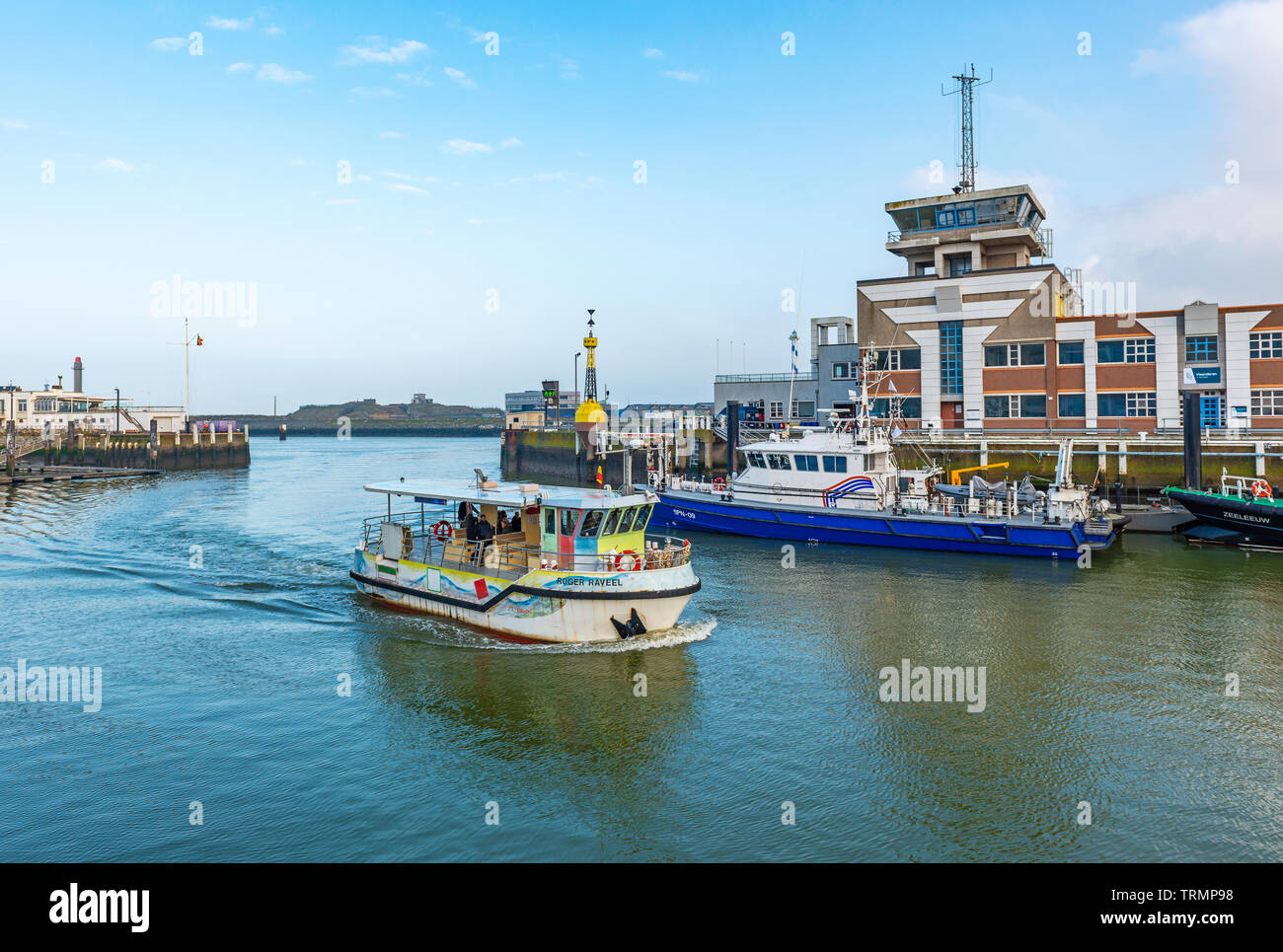 Una barca di trasporto pubblico nel porto di Ostenda (Ostenda) con l'edificio del centro del porto, Fiandre Occidentali, Belgio. Foto Stock