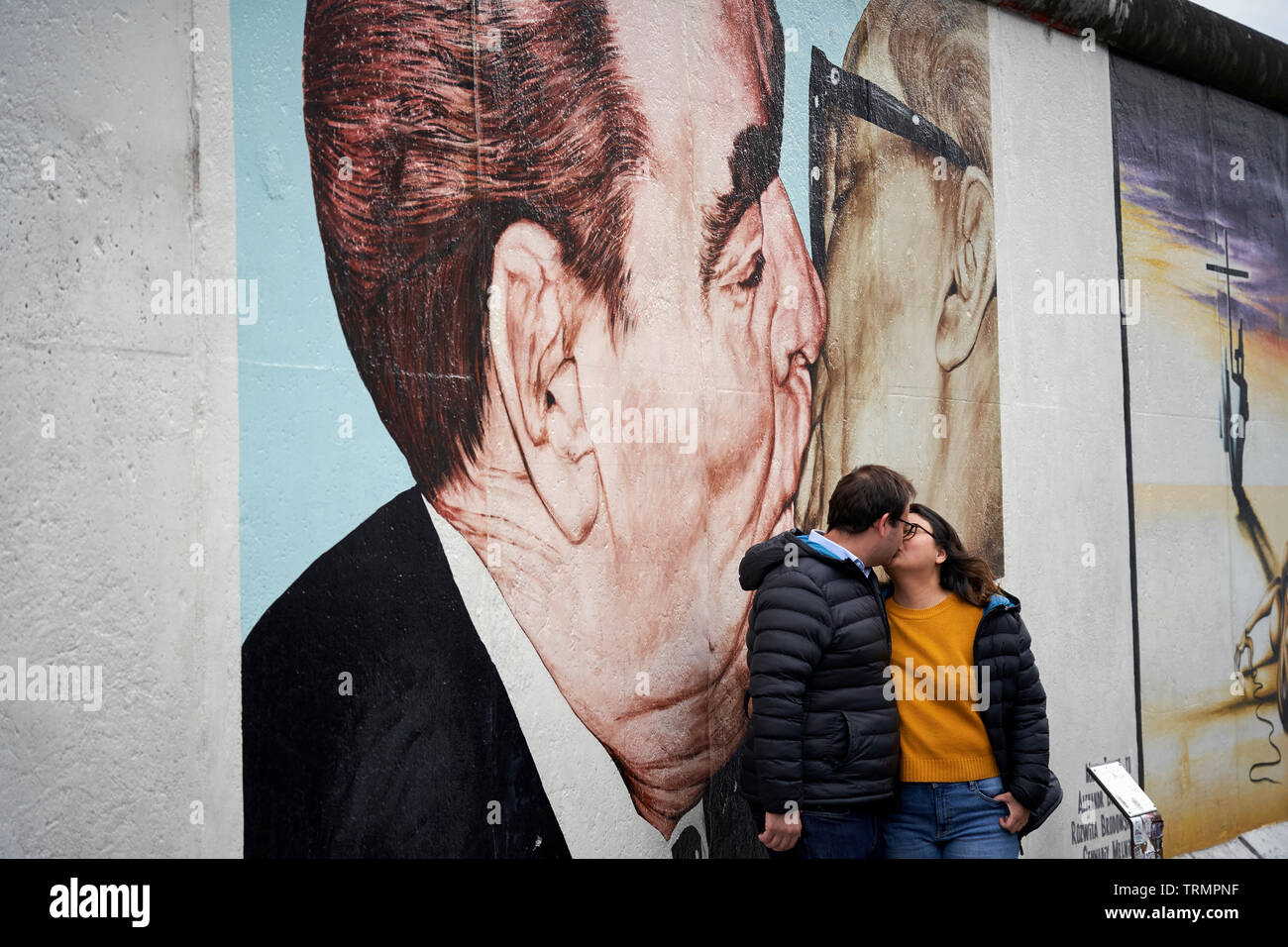 Nella East Side Gallery, un bacio di coppia di fronte alla ricreazione sul muro del bacio tra Erich Honecker e Leonidas Brezhnev. Foto Stock