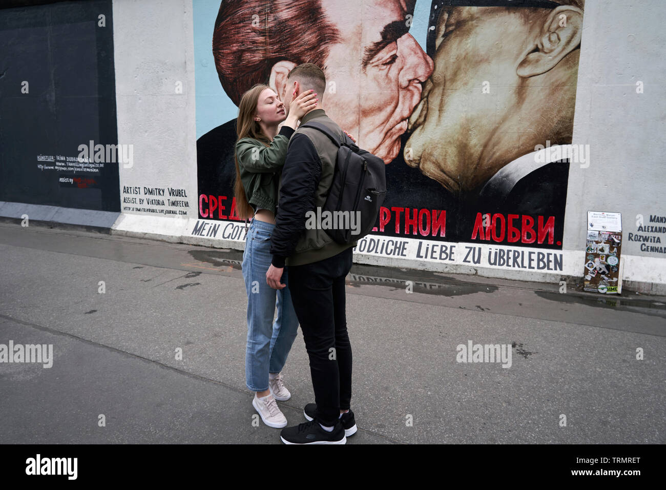 Nella East Side Gallery, un bacio di coppia di fronte alla ricreazione sul muro del bacio tra Erich Honecker e Leonidas Brezhnev. Foto Stock