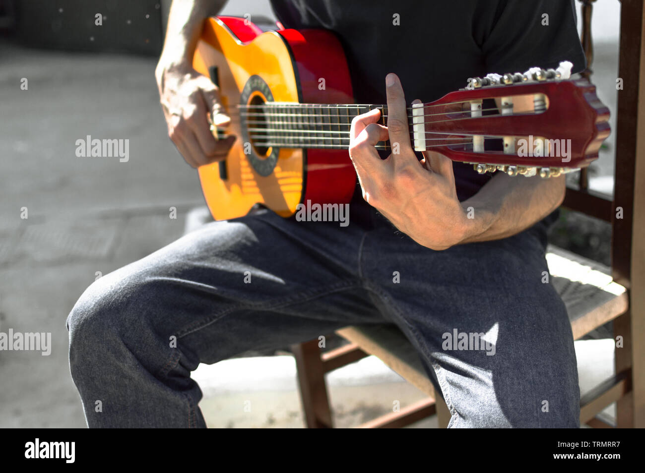 Giovane chitarrista di flamenco a suonare la chitarra seduto in una sedia  in strada in una giornata di sole. Close up di un uomo suonare la chitarra  spagnola, corda in F Foto