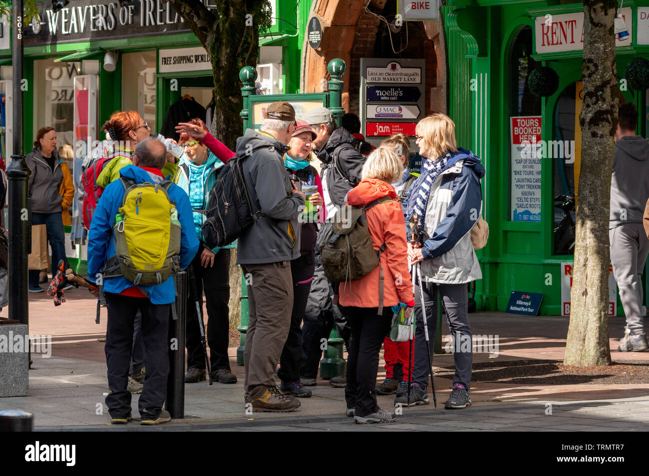 Il turismo di Killarney. I turisti in colorate giacche raccogliendo attorno a loro tour guida nel centro di Killarney. Discover Ireland guidato il gruppo turistico. Foto Stock