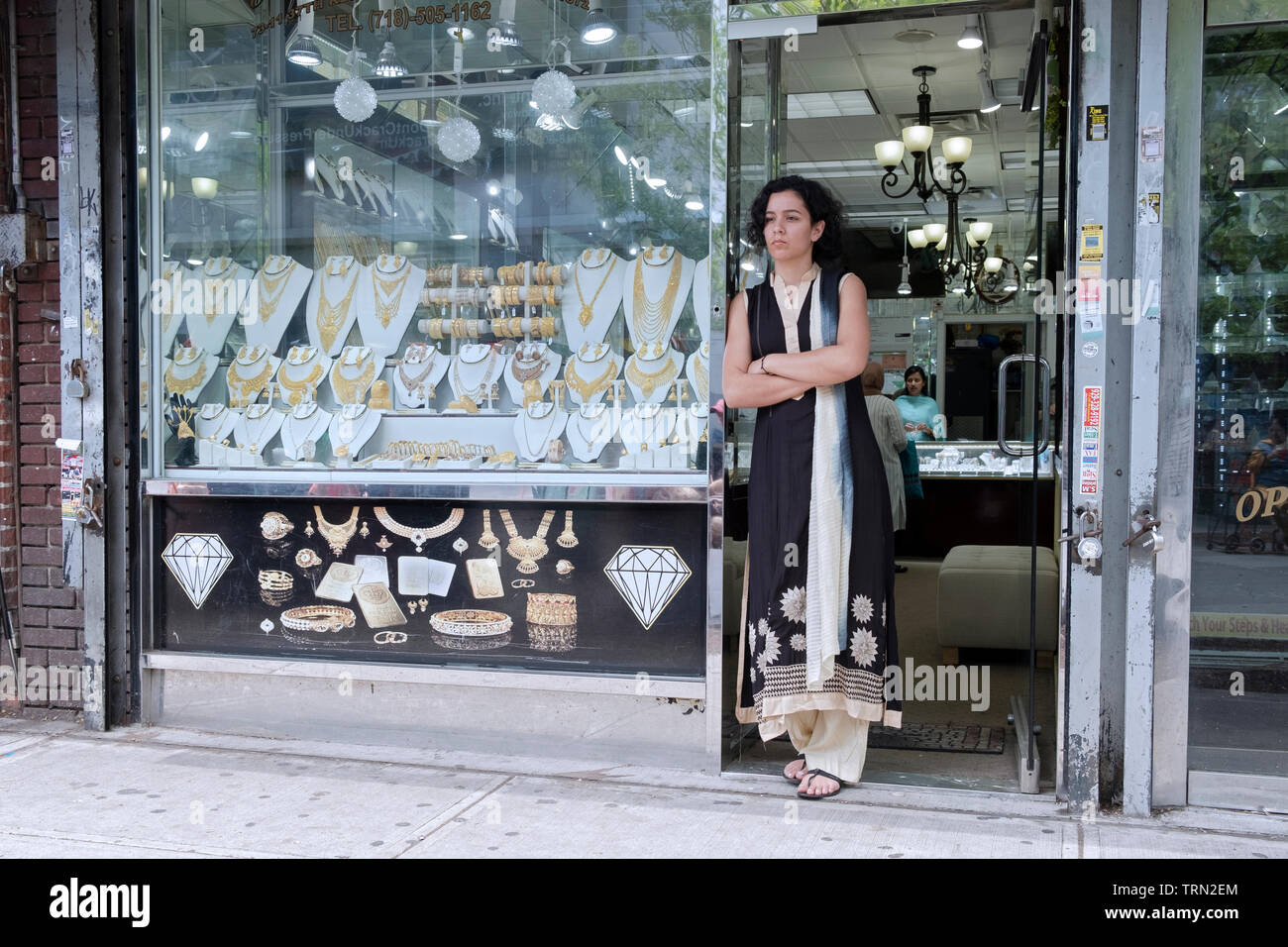 Una donna attraente in un sari in profondo pensiero al di fuori del negozio in cui lavora. La diversità Plaza, Jackson Heights, Queens, a New York City. Foto Stock