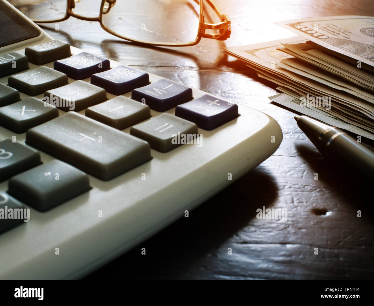 Wealth management e le finanze personali. Calcolatrice, pila di denaro e penna. Foto Stock