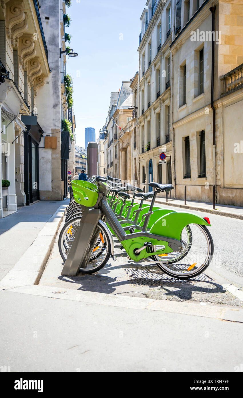 Via Parigi trasporto ibrido verde noleggio biciclette con modulo elettronico di pagamento per i viaggi in giro per la città di stand in fila sulla rete di noleggio pa Foto Stock