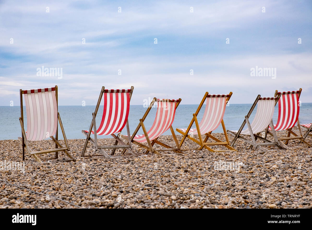 Sedie a sdraio sulla spiaggia, tipico inglese vacanza mare scena, strisce rosse e bianche Foto Stock