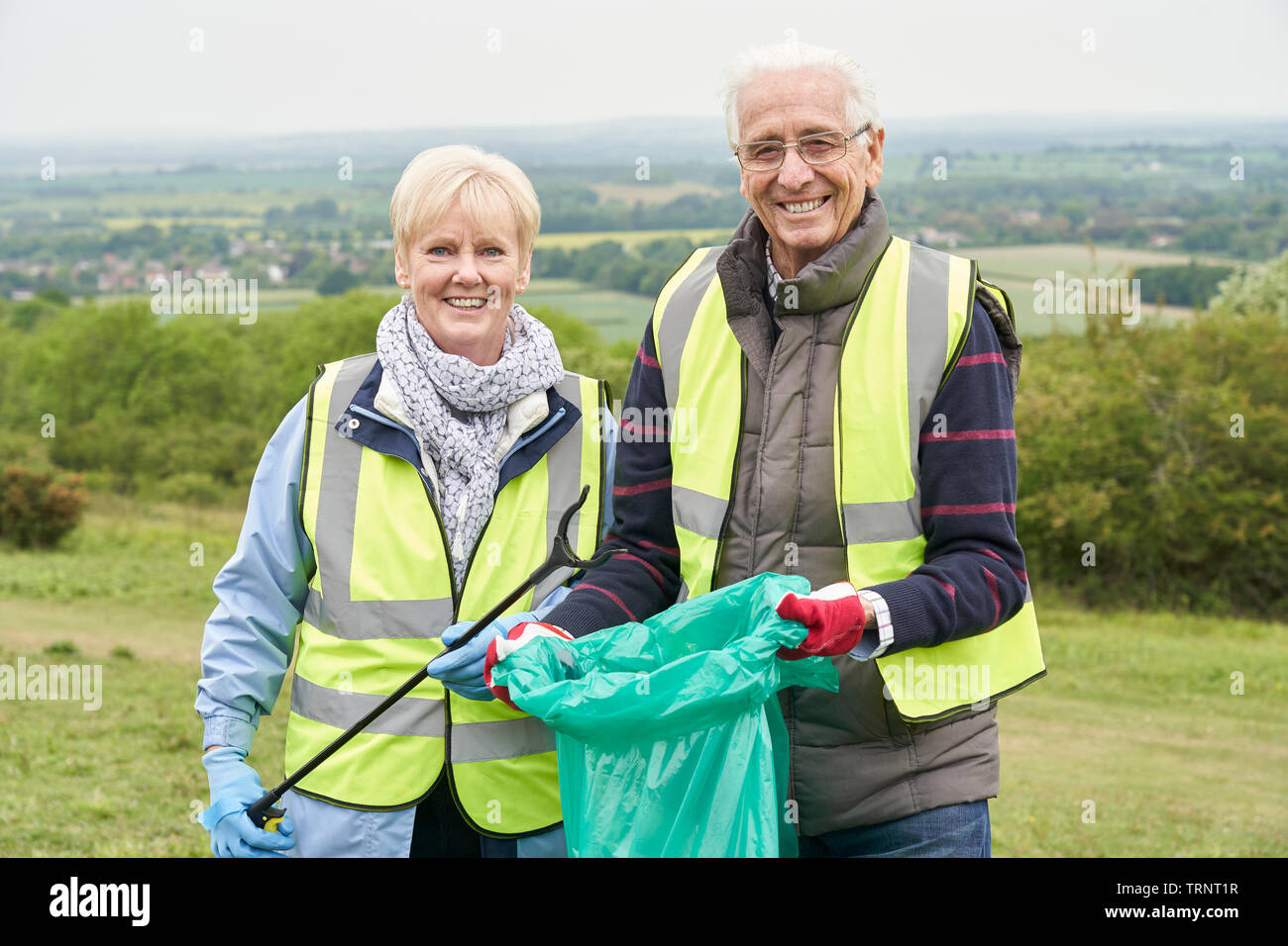 Ritratto di utile coppia Senior la raccolta di rifiuti in campagna Foto Stock