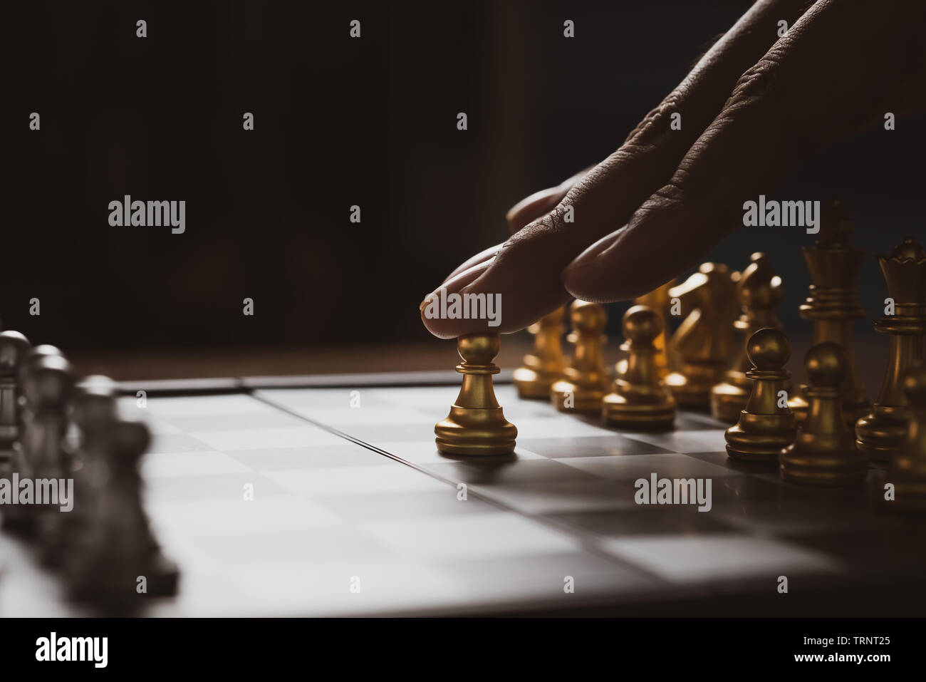 L'uomo gioca a scacchi strategia di gioco sulla scacchiera,Business piallare il concetto forte con sfondo scuro. Foto Stock
