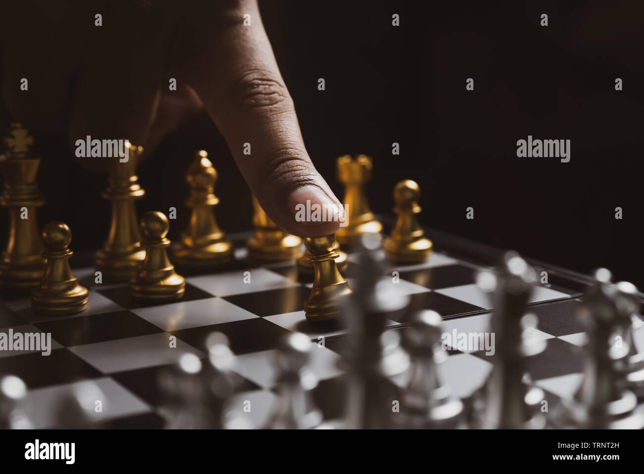 L'uomo gioca a scacchi strategia di gioco sulla scacchiera,Business piallare il concetto forte con sfondo scuro. Foto Stock
