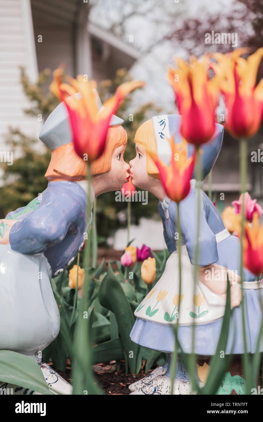 Le statue del giardino di due tradizionali olandesi baciare in un tulipano giardino circondato da colorati tulipani. Molla in Iowa. Foto Stock