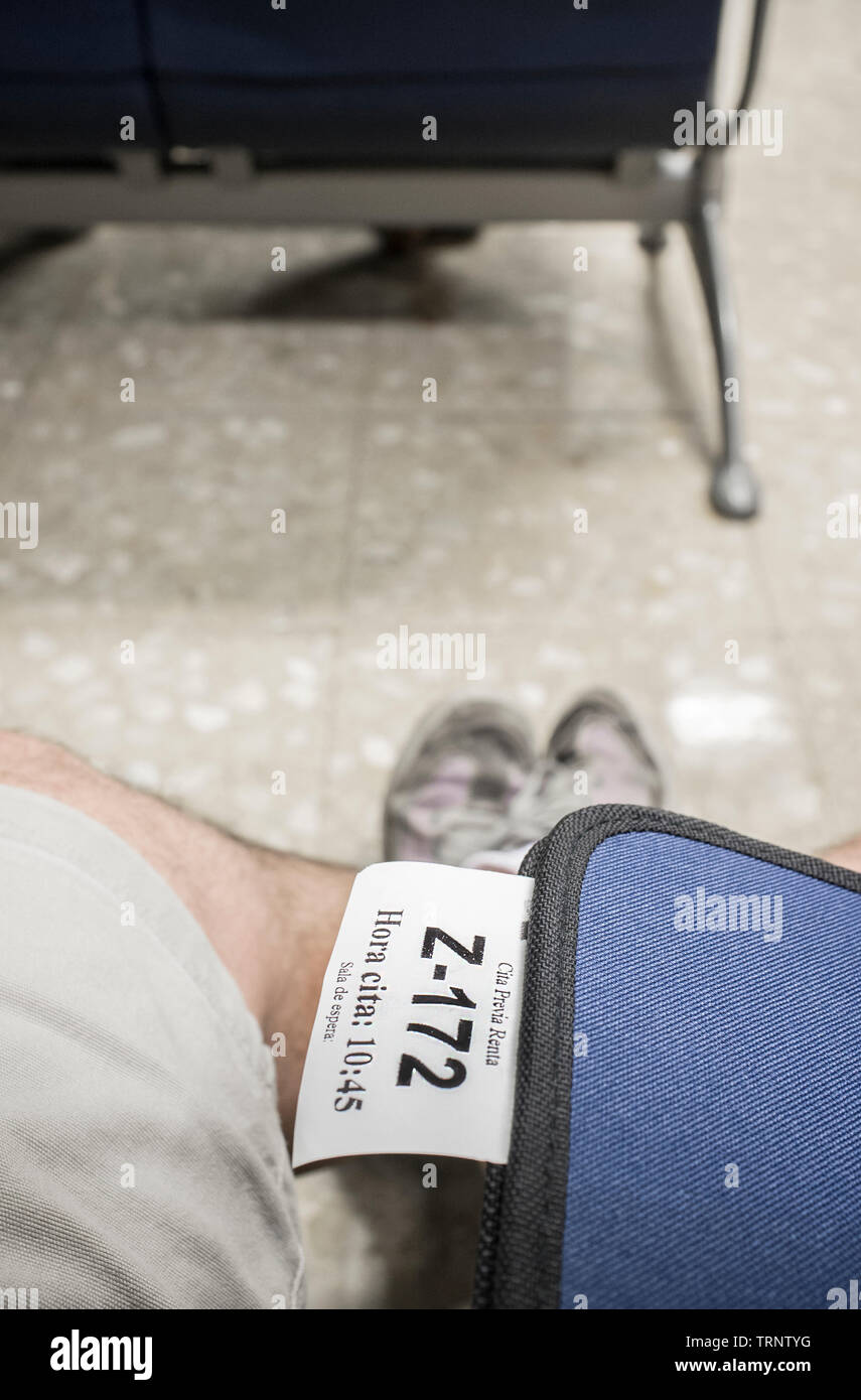 Badajoz, Spagna - Giugno 7th, 2017: la cartella con il fisco biglietto di appuntamento su maschio gambe in sala d'attesa. Dichiarazione fiscale concept Foto Stock