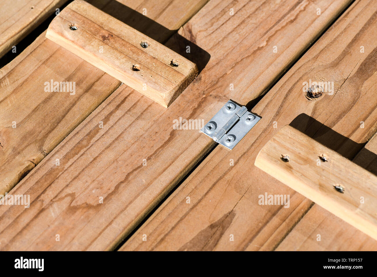 Una foto macro del coperchio di custodia di legno messo insieme con cerniere in acciaio chiodato pop e sostenuta da solidi blocchi di legno. Controllare i modelli Foto Stock