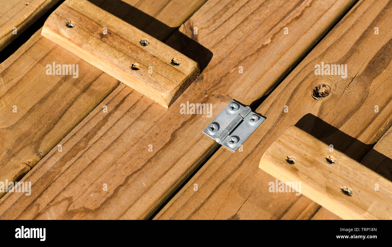 Una foto macro del coperchio di custodia di legno messo insieme con cerniere in acciaio chiodato pop e sostenuta da solidi blocchi di legno. Controllare i modelli Foto Stock