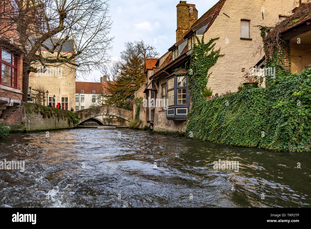 Pittoresca strada vecchia di Bruges con tradizionali case medievali, edera, canal e ponti. La città di Bruges strade girato dalla barca. Foto Stock