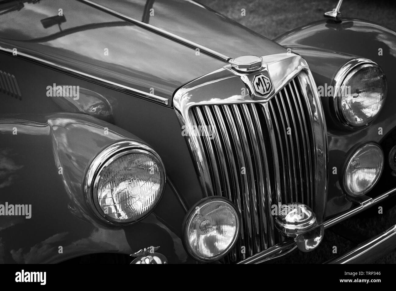 Immagine in bianco e nero dell'estremità anteriore di uno storico classic vintage MGA auto sportiva che mostra FARI E CALANDRA MG badge e parti tirate a lucido. Foto Stock