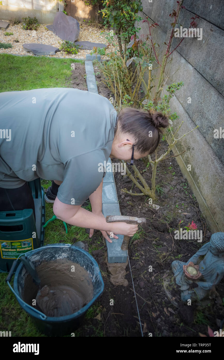 Giovane donna di costruzione di una parete in un giardino Foto Stock