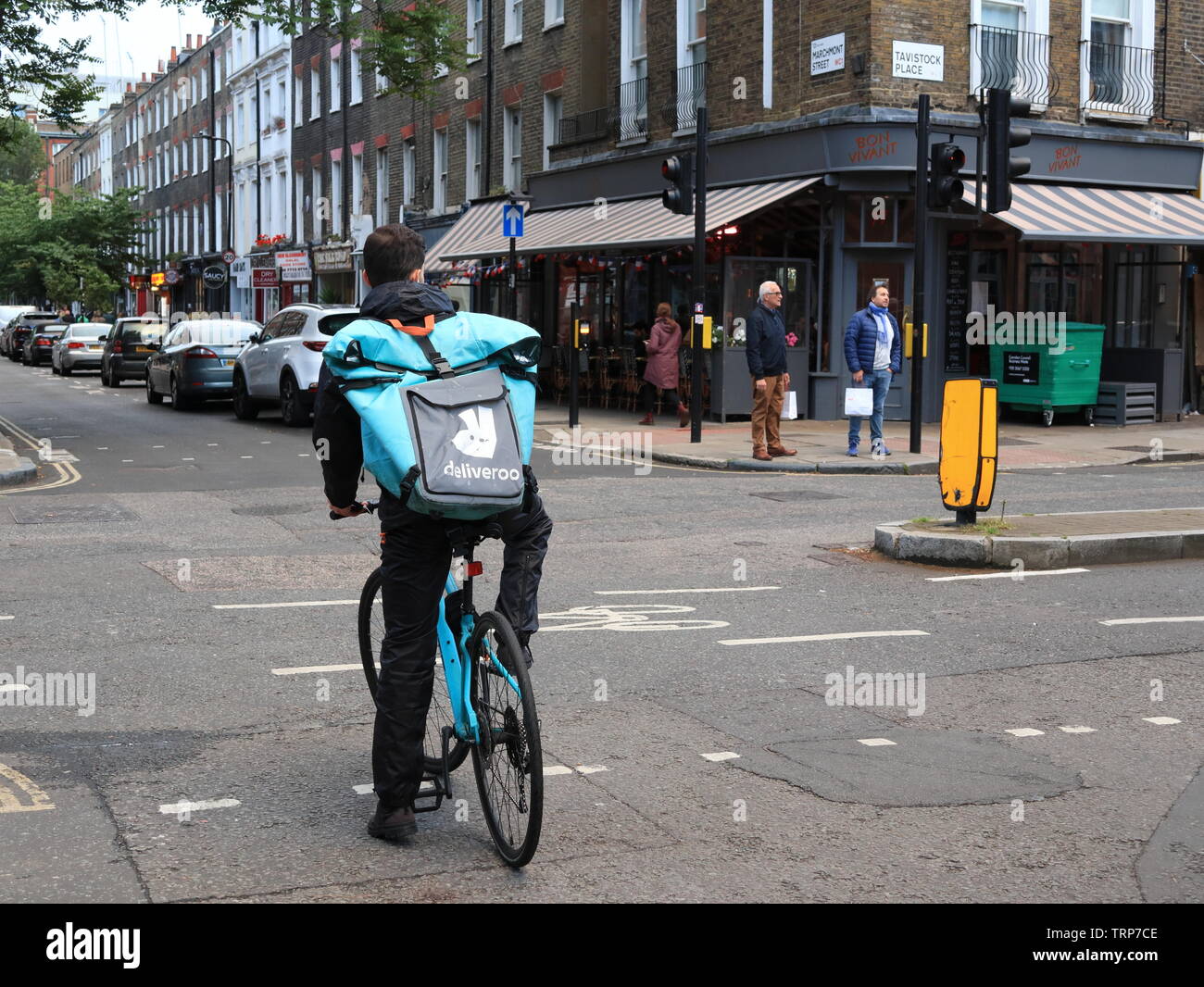 Deliveroo rider in attesa al bivio, London, England, Regno Unito Foto Stock