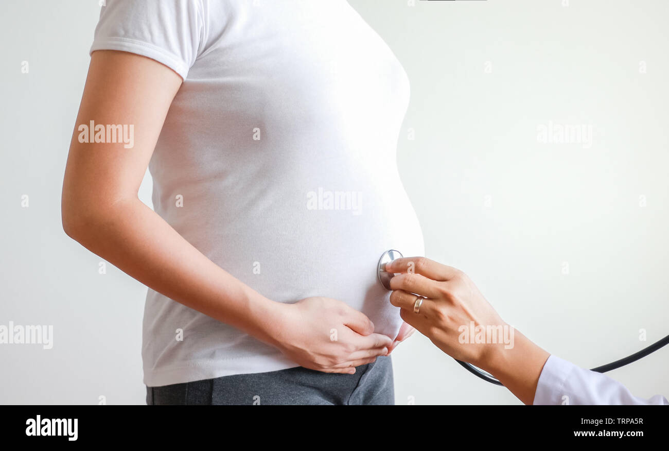 Donna incinta ascoltare baby battito cardiaco con stetoscopio medico Foto Stock