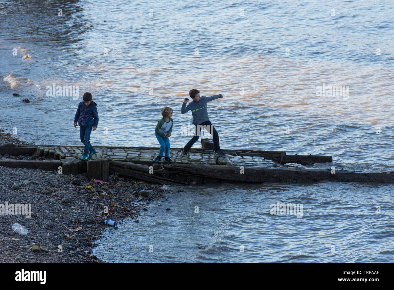 Kinder werfen Steine in die Themse. // I bambini scagliare pietre nel fiume Thames, London. // Des Enfants jettent des pierres dans la Tamise, Londres. Foto Stock