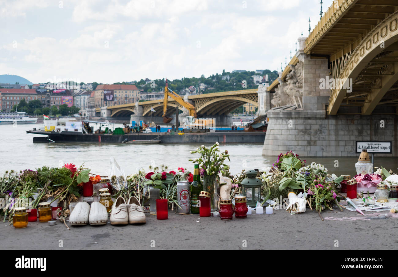 Omaggi a Budapest compresi fiori, candele e paia di scarpe poste dalla riva presso il sito di un incidente in cui due imbarcazioni si sono scontrate. Foto Stock