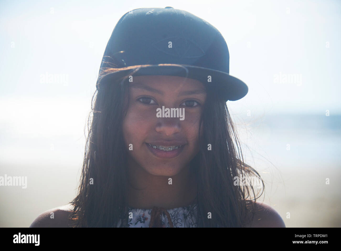 Ritratto di un giovane adolescente ragazza asiatica che indossa un nero cappello da baseball in spiaggia in una giornata di sole Foto Stock