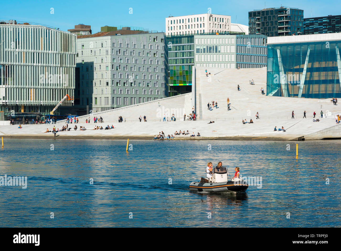 Oslo Norvegia, vista di giovani la vela una barca passato il Teatro dell'Opera di Oslo e la città del distretto di codici a barre su un pomeriggio d'estate, Norvegia. Foto Stock