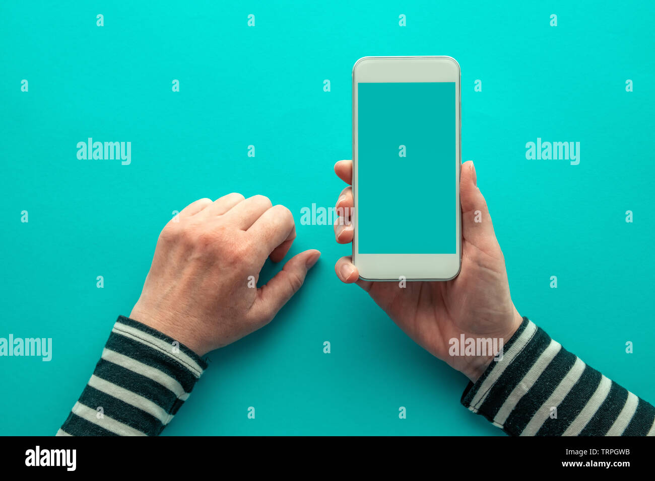 Vista superiore dello smartphone mock up su mani femminili su sfondo blu Foto Stock