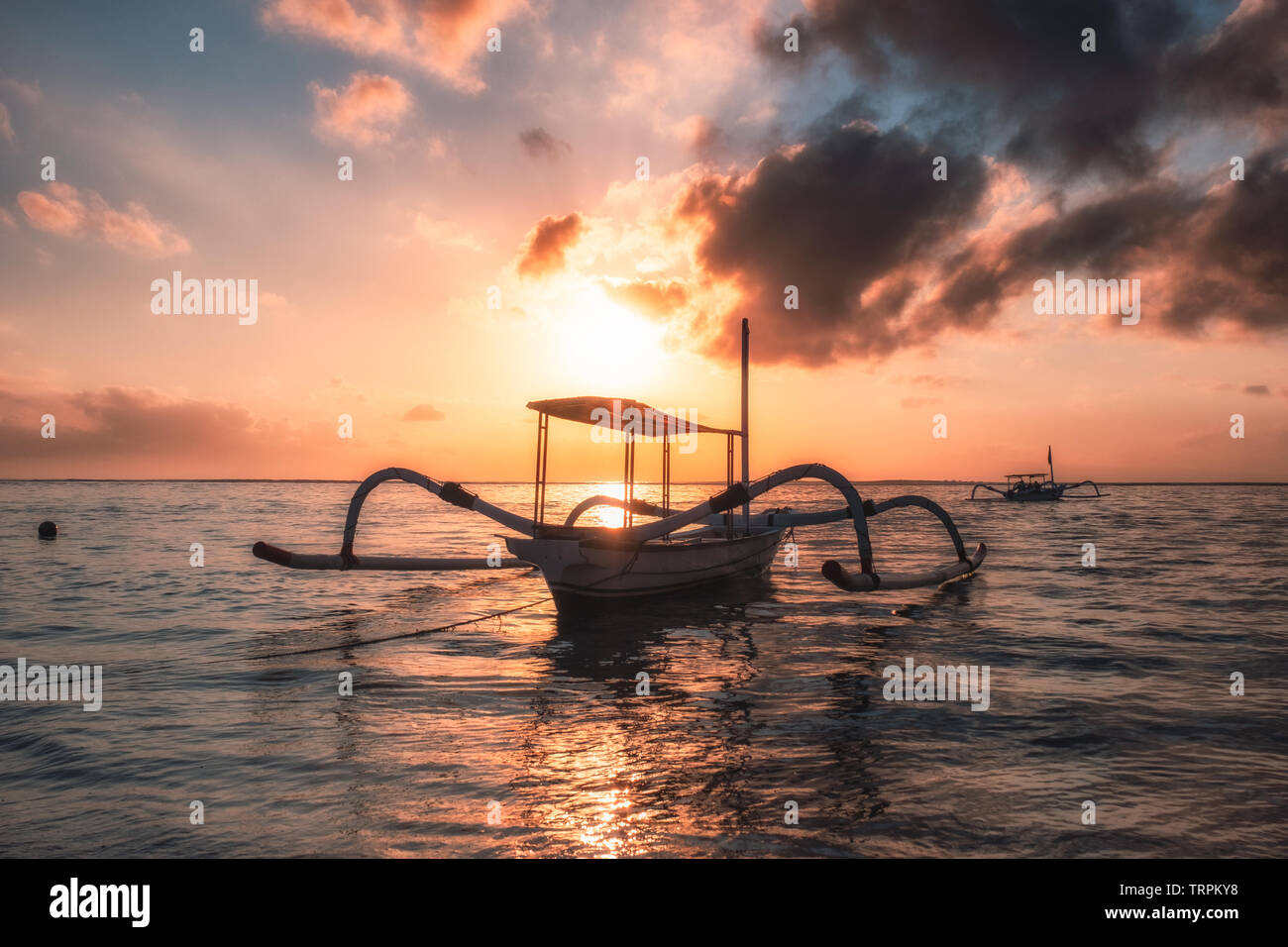 Antica Jukung tradizionali barche da pesca sulla spiaggia al tramonto colorato. Sanur Beach, Bali, Indonesia Foto Stock