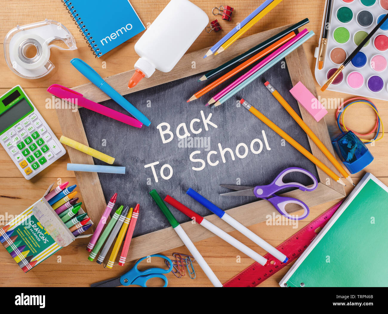 Si torna a scuola scritto su una lavagna circondata da un vasto assortimento di forniture scolastiche Foto Stock