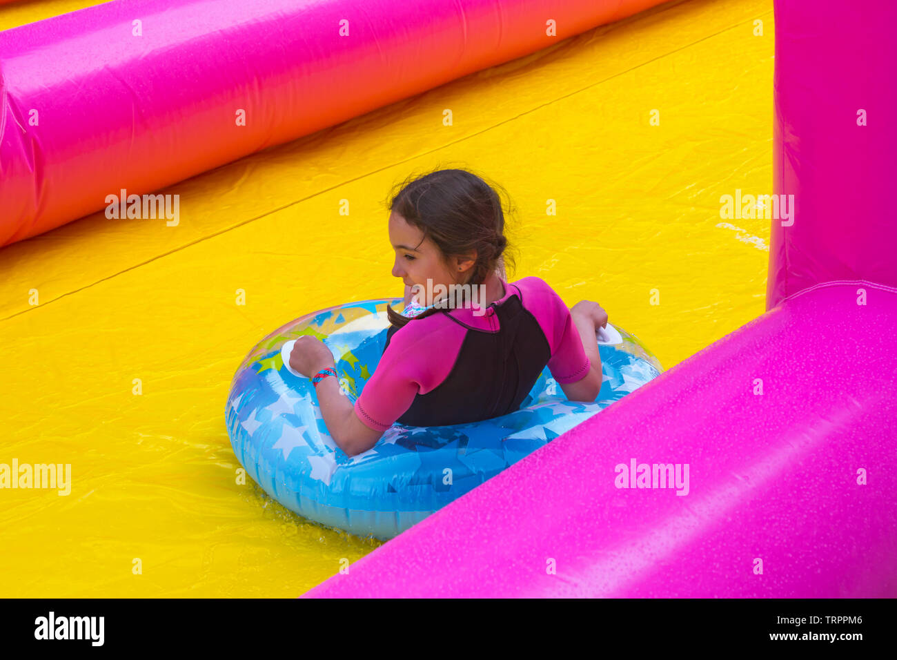 Ragazza sull anello gonfiabile avente divertimento sul waterslide gigante, scivolo d'acqua, a Bournemouth Dorset UK in giugno Foto Stock