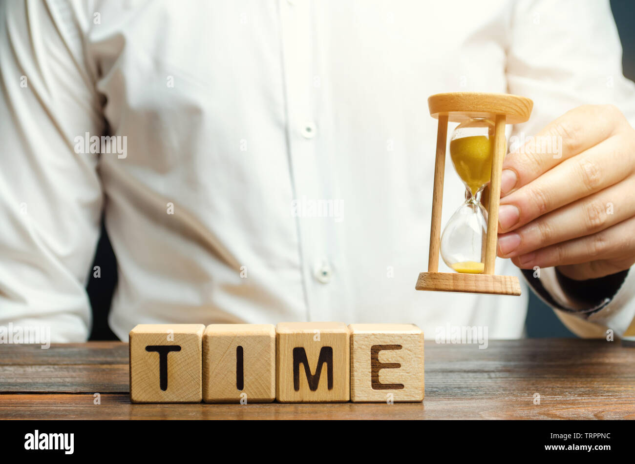 Un uomo mette i blocchi di legno con il tempo di parola. Concetto di gestione del tempo e la distribuzione corretta. Attività di pianificazione e di lavoro. Business della gioventù. Analisi Foto Stock
