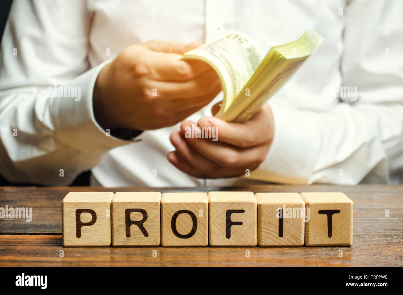 Blocchi di legno con la parola profitto e un uomo che conta il denaro. Il risultato finanziario della società per un certo periodo di tempo. Reddito. Torna su inv Foto Stock