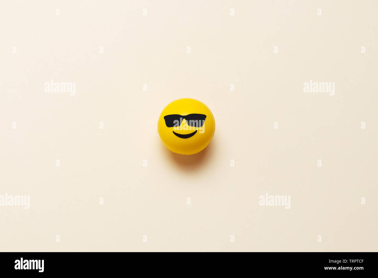 Faccina sorridente sfera con occhiali da sole su sfondo pastello Foto Stock