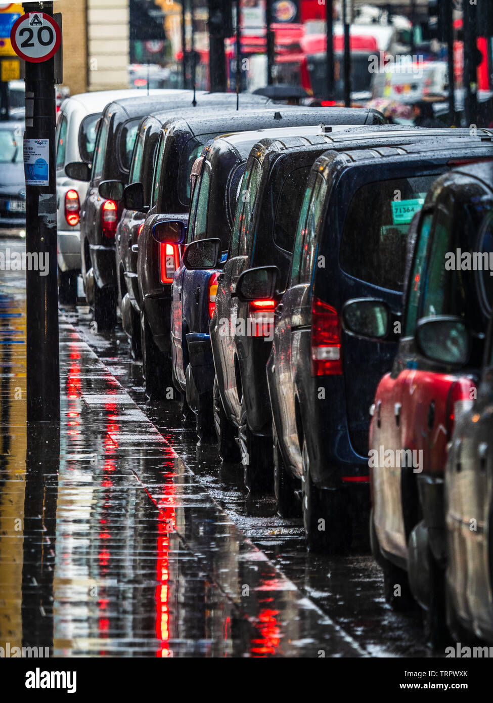 Taxi a Londra sotto la pioggia - una coda di London Black Cabs in attesa per i passeggeri sotto la pioggia battente Foto Stock