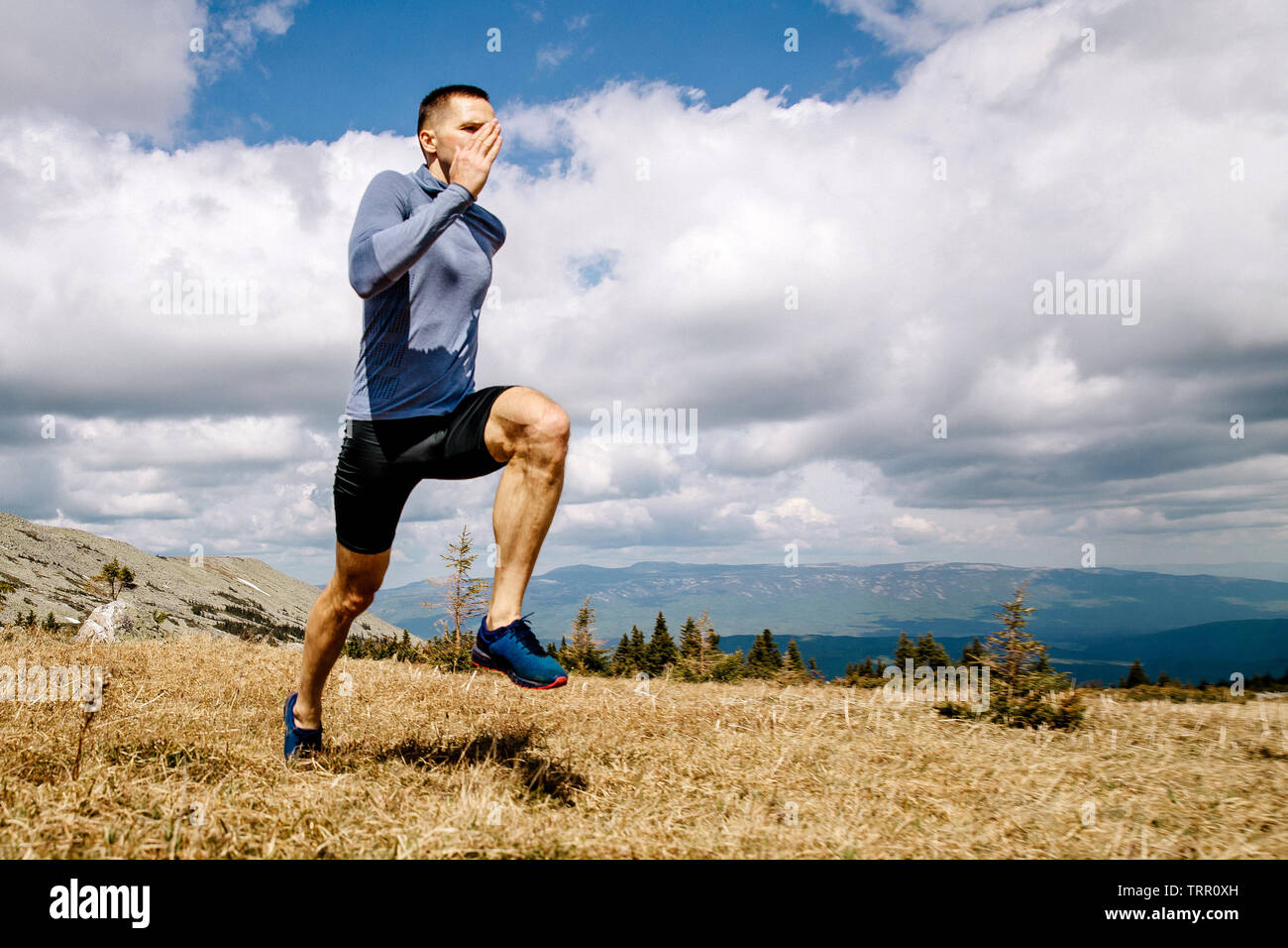 L'uomo atleta che corre sulla montagna altopiano di sfondo cielo blu e nuvole Foto Stock