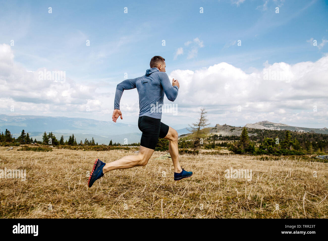 Runner maschio cross country in esecuzione sul sentiero di montagna in estate all'aperto Foto Stock