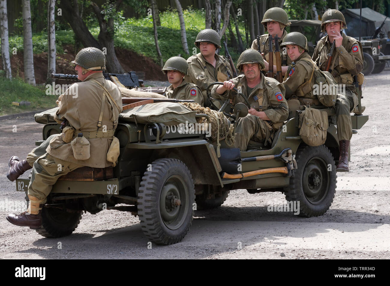 Sette reenactors vestiti come soldati dell'esercito statunitense ottantaduesima Airborne "tutti Americani" divisione su una jeep Foto Stock