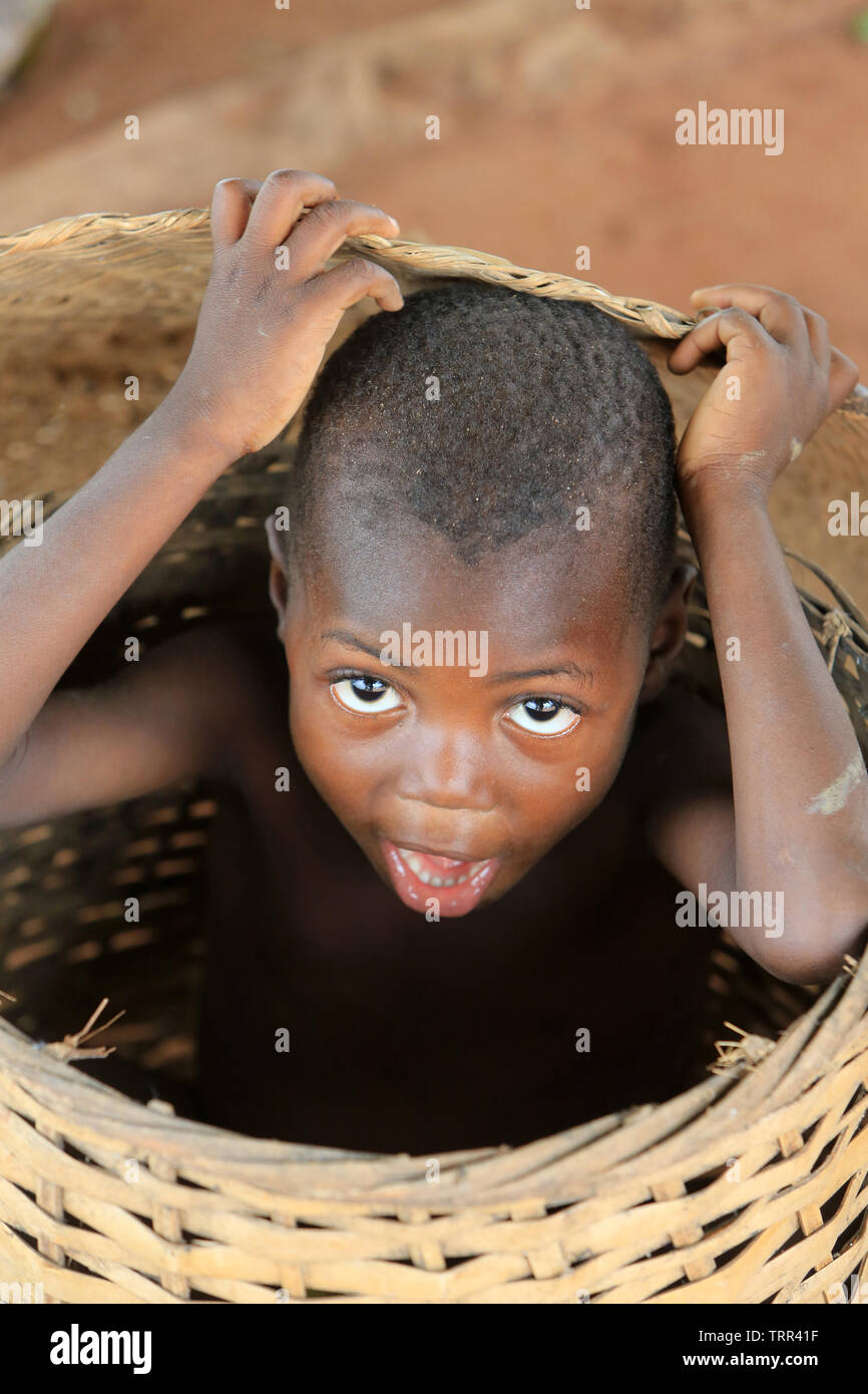 Ritratto d'onu enfant togolais se cachant dans un panier en vimini. Togoville. Il Togo. Afrique de l'Ouest. Foto Stock