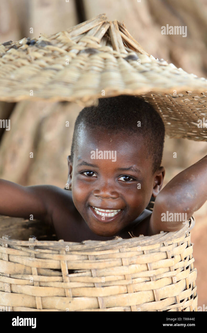 Ritratto d'onu enfant togolais se cachant dans un panier en vimini. Togoville. Il Togo. Afrique de l'Ouest. Foto Stock