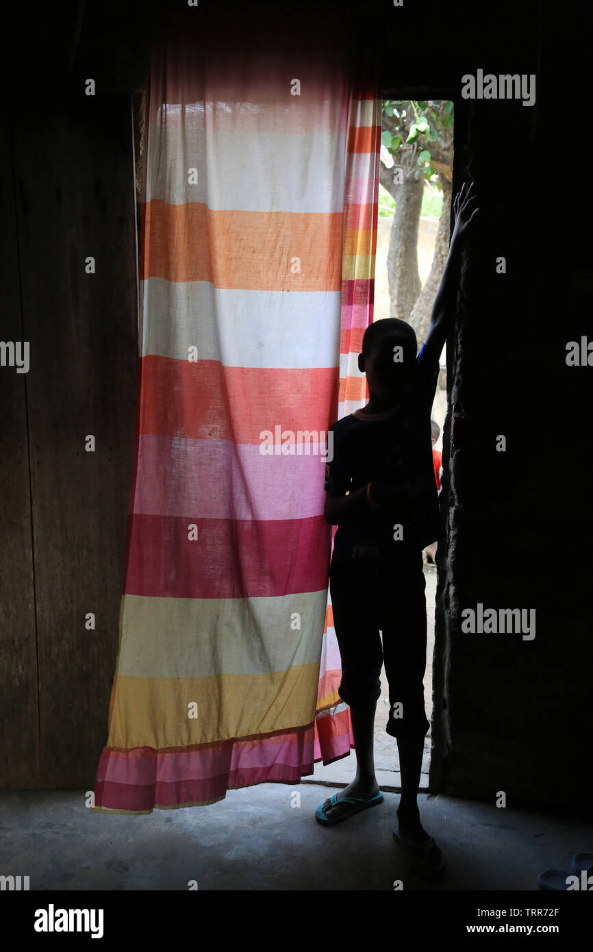 Silhouette d'onu enfant dans l'entrée de figlio di abitazione. Datcha. Il Togo. Afrique de l'Ouest. Foto Stock