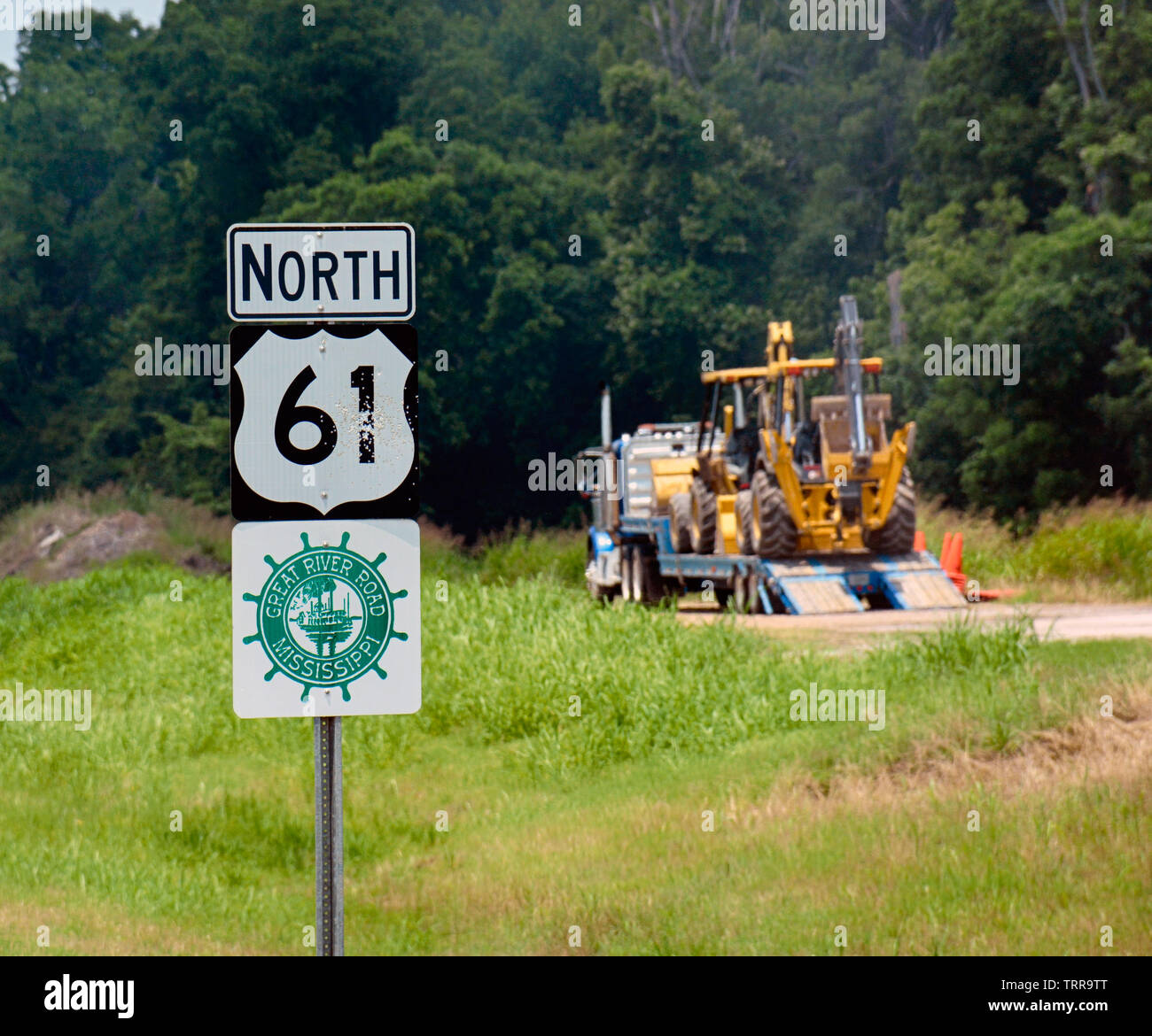 Un bulldozer su un rimorchio di un trattore rig è parcheggiato a fianco di un'autostrada segno per il Nord 61, nel nord-ovest del Mississippi, lungo la storica grande Foto Stock