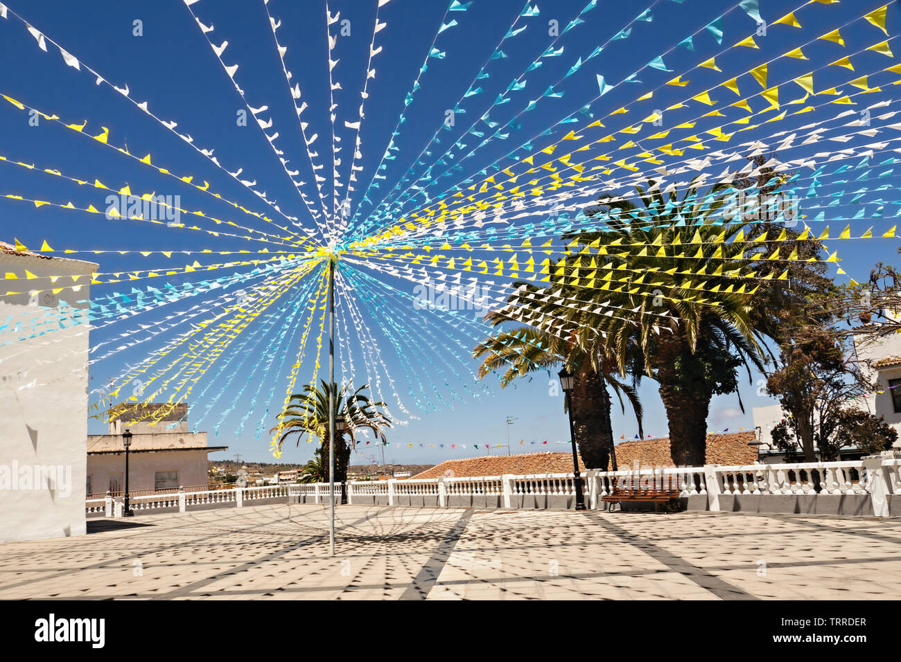 Una piazza della chiesa decorata con ghirlande colorate per una festa tradizionale in Tenerife. Il blu-bianco-bandiere gialle soffiare il vento al di sotto di un blu scuro Foto Stock