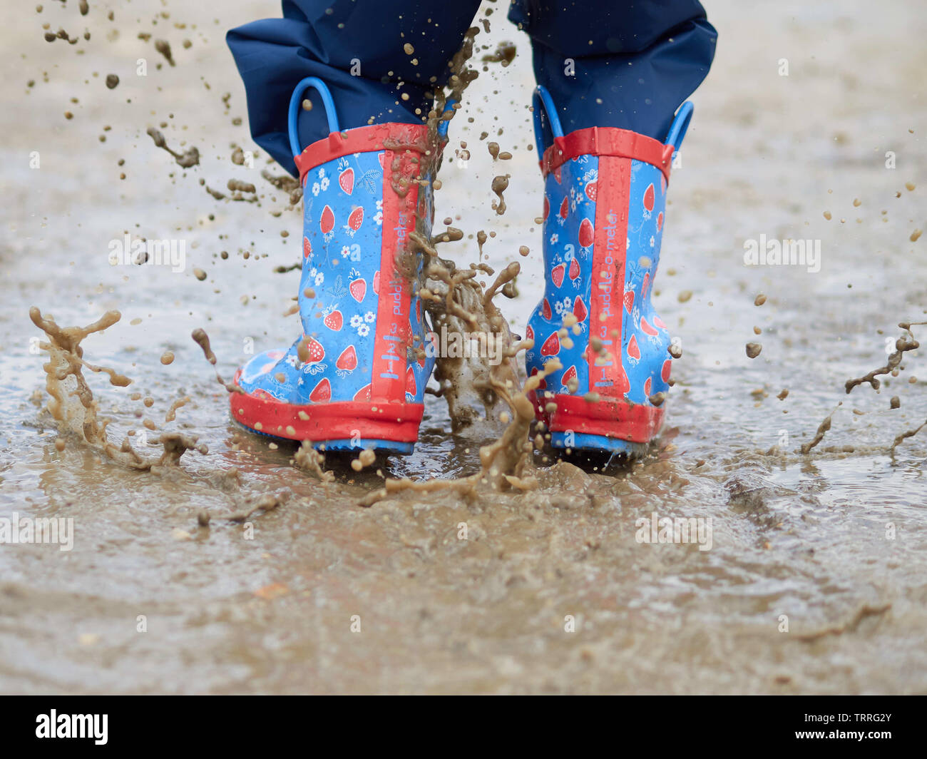 Schizzi di salto del bambino stivali da pioggia nella pozza - Manvers, South Yorkshire, Regno Unito Foto Stock