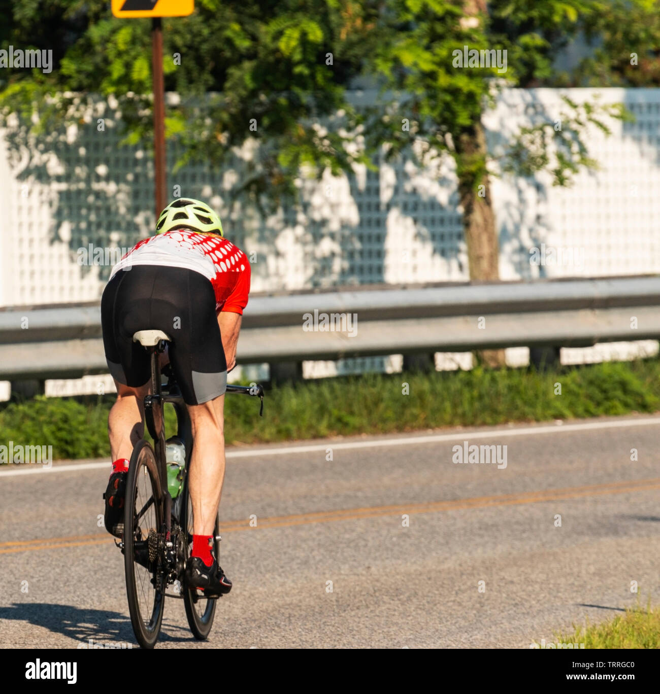 Un ciclista cacciato lontano dalla telecamera il training su strade su una soleggiata mattina d'estate. Foto Stock