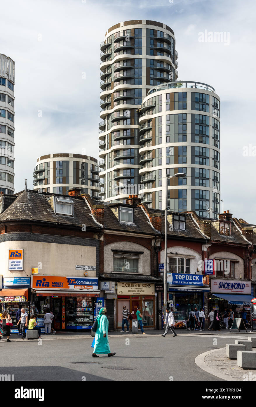 London, England, Regno Unito - 1 Giugno 2019: pedoni a piedi passato negozi indipendenti sulla stazione Parade di Barking Town Center, con la nuova build di alto-aumento apartme Foto Stock