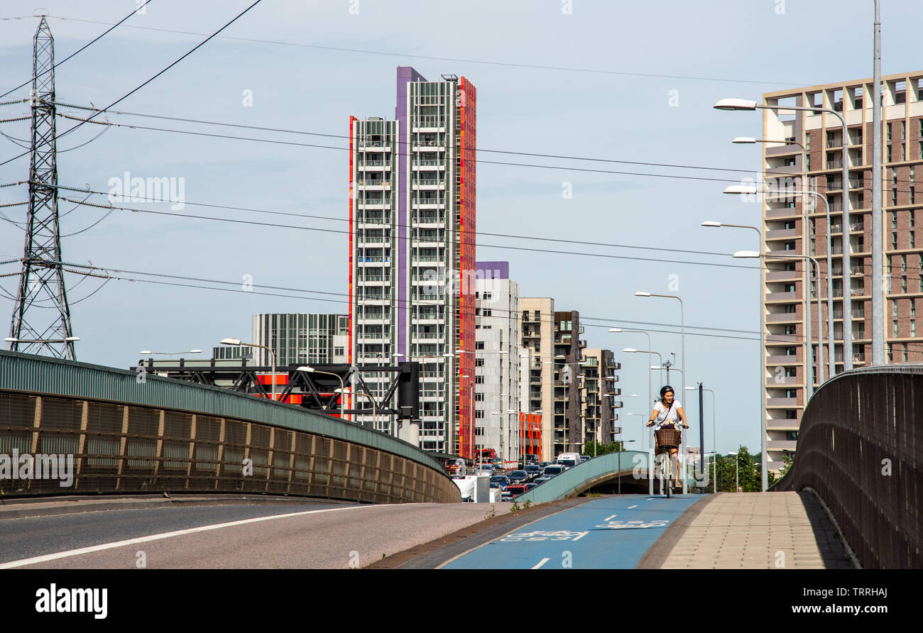 London, England, Regno Unito - 1 Giugno 2019: Un ciclista viaggia lungo il superhighway di ciclo 3 passato nuova build alta edifici di appartamenti in la Canning Town neighb Foto Stock