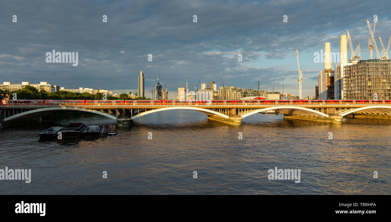 London, England, Regno Unito - 28 Maggio 2019: un treno Gatwick Express che passa Battersea Power Station come si attraversa il fiume Tamigi nella zona ovest di Londra. Foto Stock